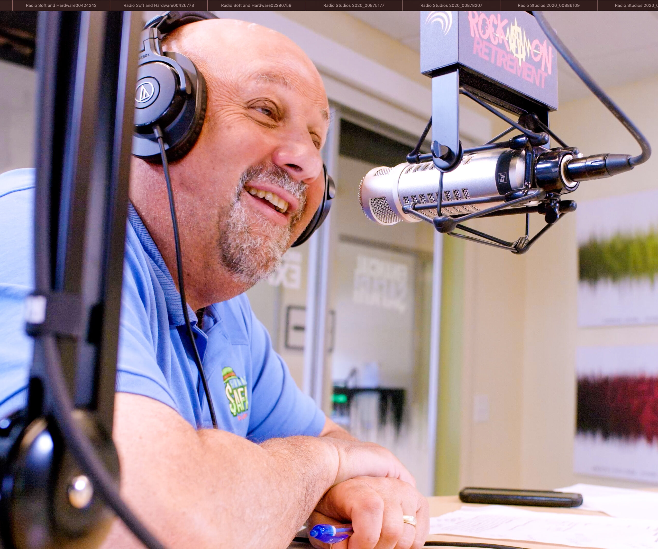 An experienced radio host in a large radio studio sitting behind a microphone.