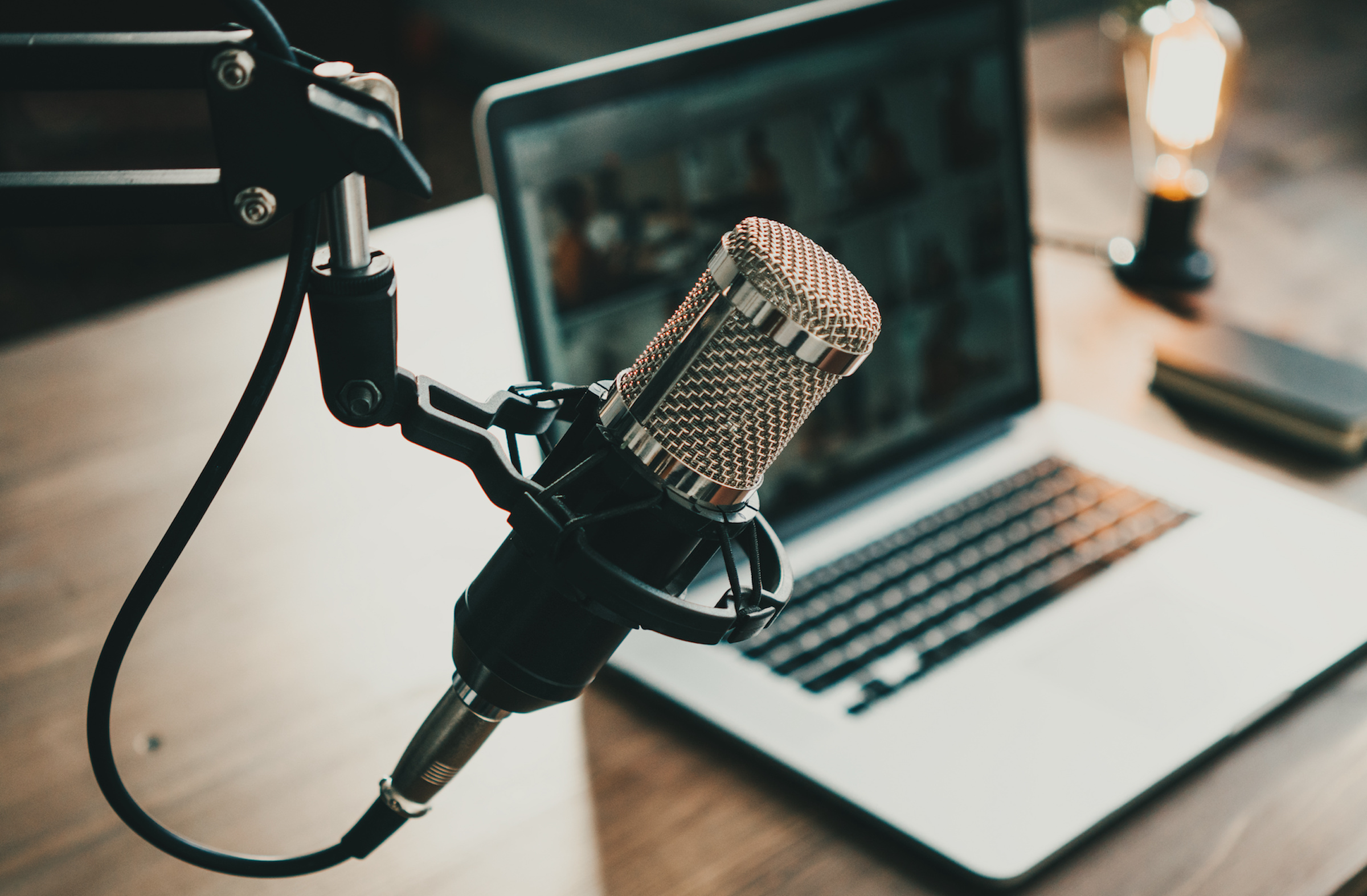 Home studio podcast interior. Microphone, laptop and on air lamp on the table, close-up